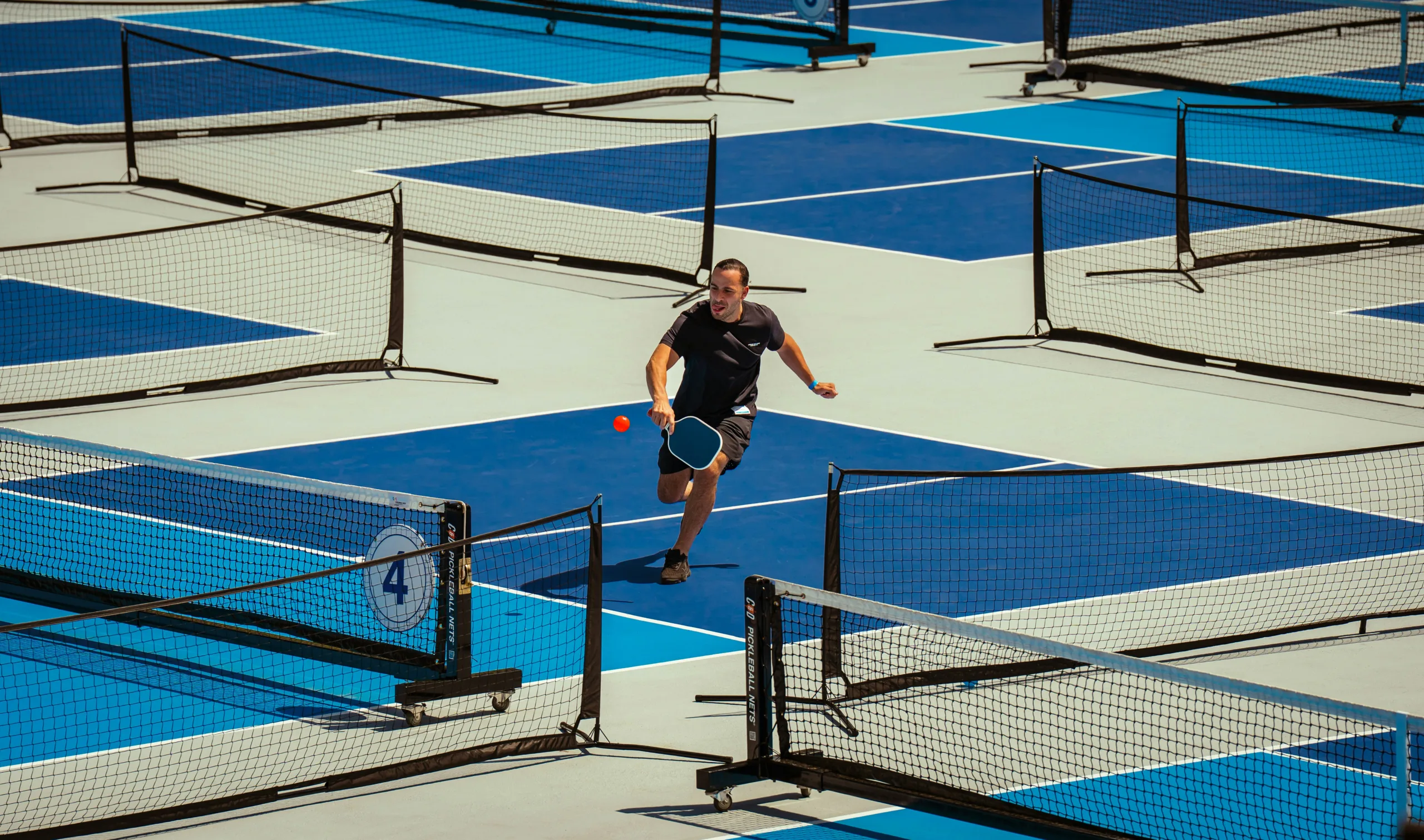 A man plays pickleball on an outdoor court.